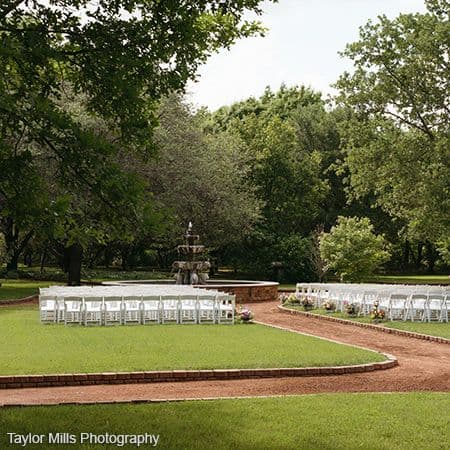 The garden lawn at Clark Gardens set up with white chairs for a ceremony